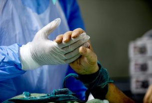 Covid-19 ασθενής αφυπνίζεται από την καταστολή και σφίγγει χέρι του ιατρού εντατικολόγου Κωστή Ποντίκη (Απρίλιος 2020) Φωτογραφία: Γιώργος Μουτάφης | Σχεδιασμός: Ευγένιος Καλοφωλιάς